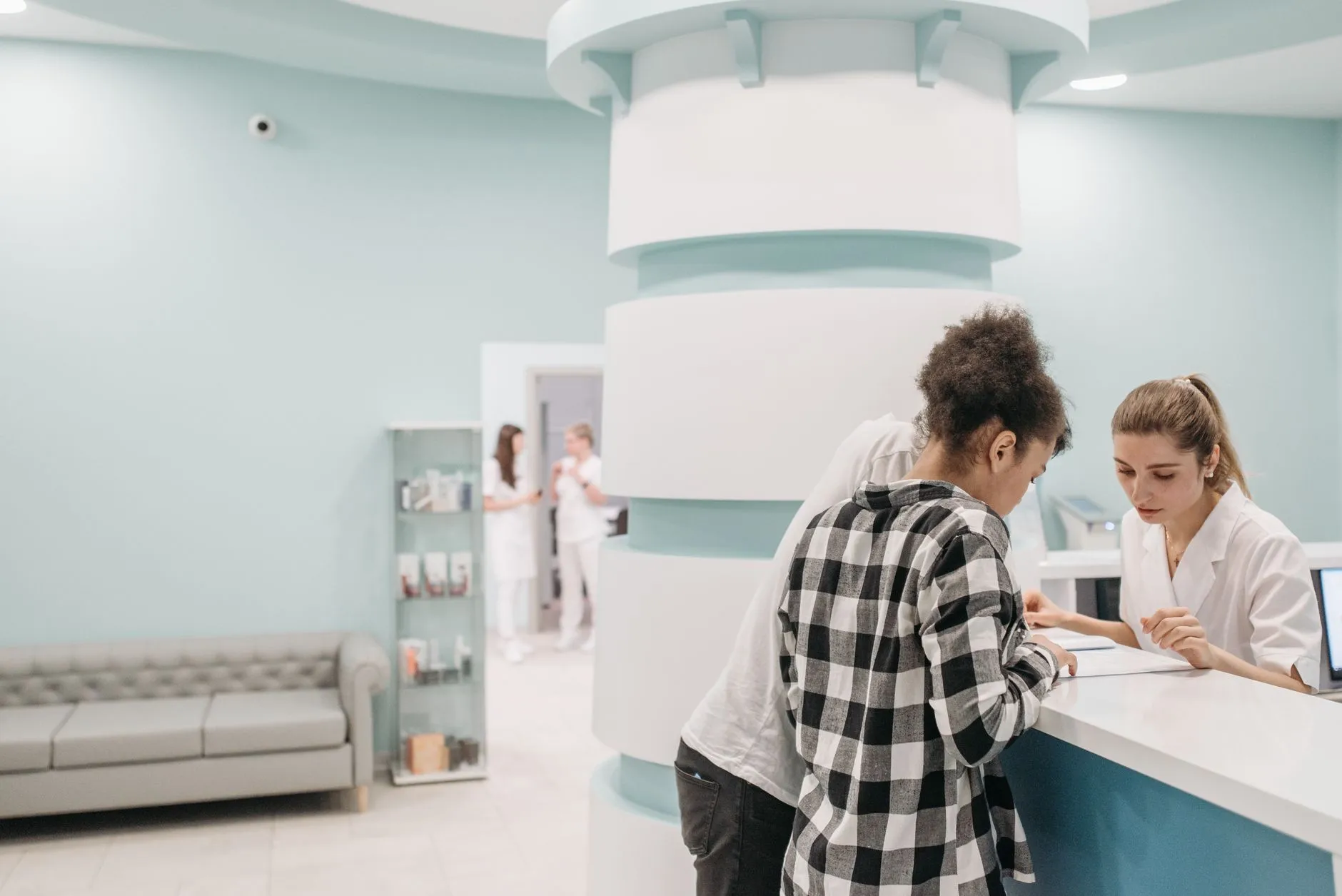 Staff at a clinic reception desk helping someone check in.