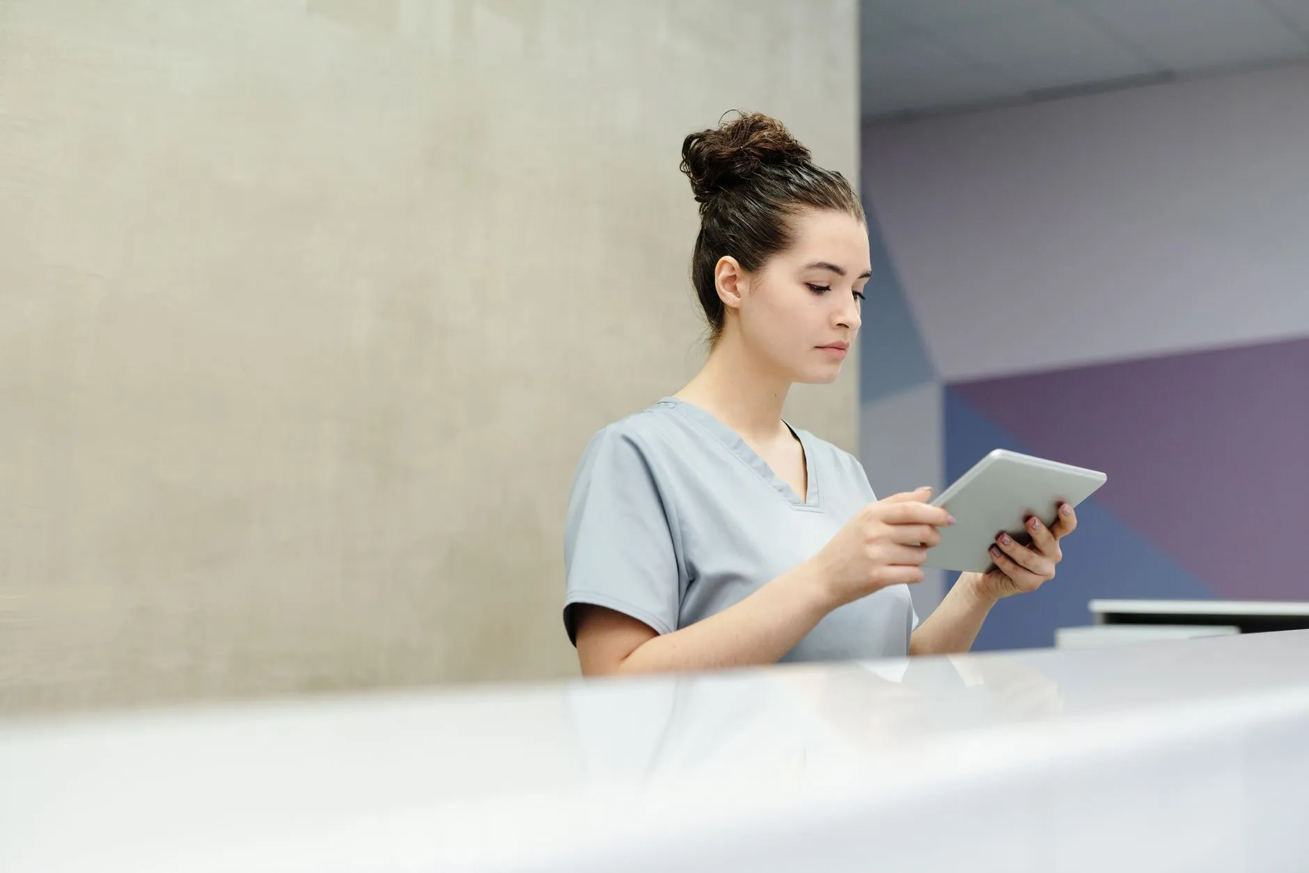 A receptionist entering details on a tablet at a front desk.
